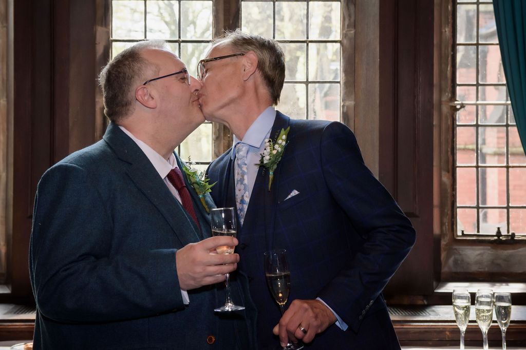 two husbands kissing each other during their drinks reception at their same sex wedding in Liverpool. Wedding day photography by Michael Pardoe