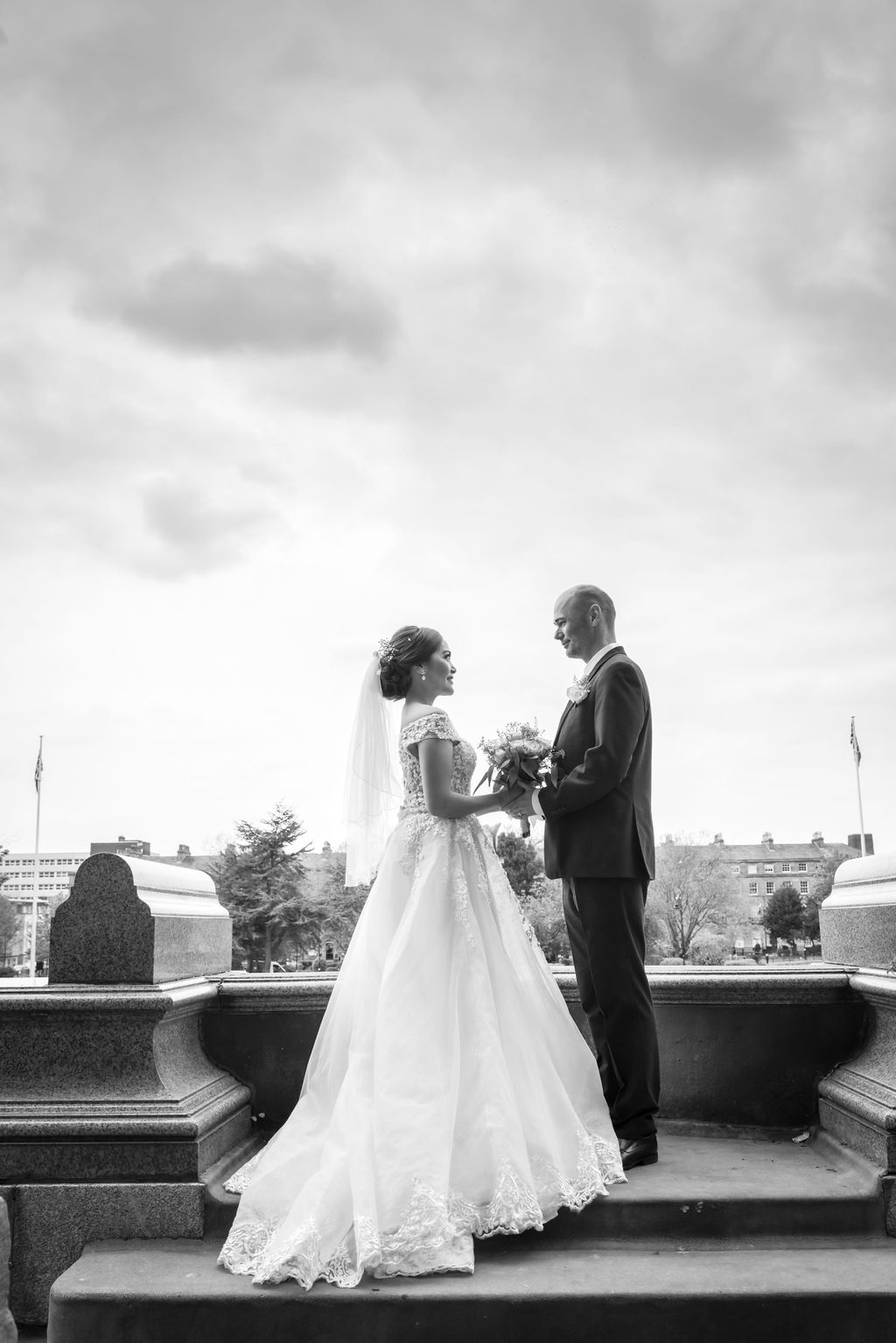 a black and white wedding photograph of a bride and groom holding hands and looking at each other stood outside Birkenhead Town Hall