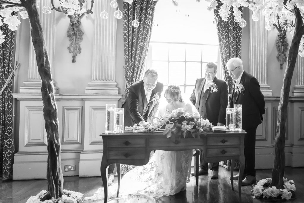 knowsley hall wedding and the bride and groom signing the register