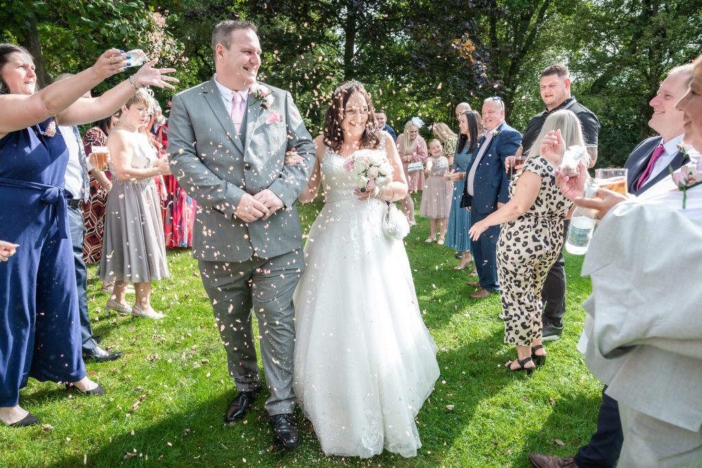 Happy couple celebrates wedding in Stockport with joyful confetti toss. Stunning photo by Cheshire wedding photographer Michael Pardoe.