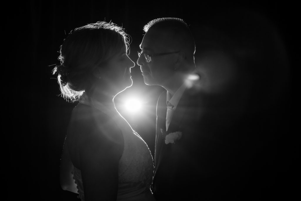 Timeless black and white wedding photo: bride and groom silhouette illuminated by dramatic off-camera flash. Capturing the magic of their love on their special day. #weddingphotographer #weddingphotography #blackandwhiteweddingphoto